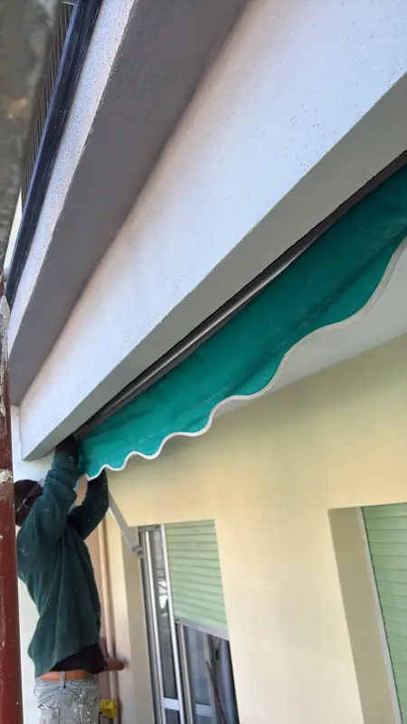 Operaio che lavora sotto un balcone con la tenda verde