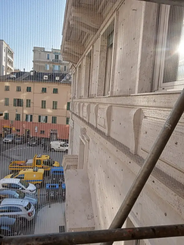 Palazzo in pietra visto dal ponteggio, con la piazza e le auto parcheggiate sotto