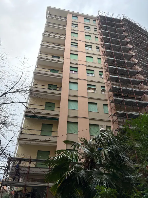 Palazzo rosa di dieci piani con il ponteggio montato sul fianco