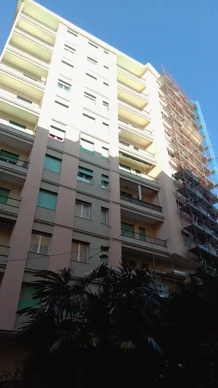Facciata chiara di un palazzo con il ponteggio sull'ala destra, cielo azzurro